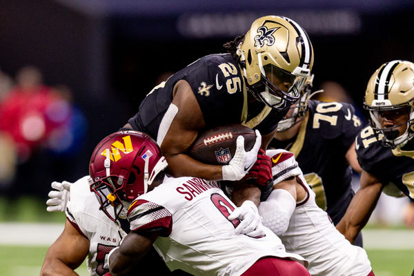 Dec 15, 2024; New Orleans, Louisiana, USA;  New Orleans Saints running back Kendre Miller (25)  is tackled by Washington Commanders cornerback Mike Sainristil (0) during the second half at Caesars Superdome. Mandatory Credit: Stephen Lew-Imagn Images