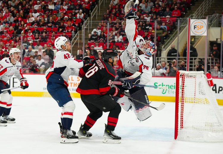 Nov 3, 2024; Raleigh, North Carolina, USA;  Washington Capitals goaltender Charlie Lindgren (79) reaches for the puck with defenseman Martin Fehervary (42) and Carolina Hurricanes defenseman Sean Walker (26) at Lenovo Center. Credit: James Guillory-Imagn Images