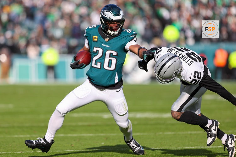 Dec 14, 2025; Philadelphia, Pennsylvania, USA; Philadelphia Eagles running back Saquon Barkley (26) runs the ball against Las Vegas Raiders cornerback Eric Stokes (22) during the first quarter at Lincoln Financial Field. Credit: Bill Streicher-Imagn Images