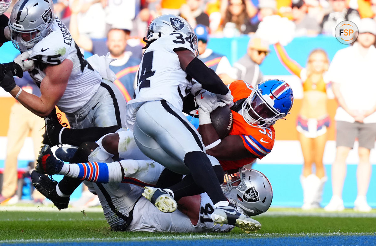 Oct 6, 2024; Denver, Colorado, USA; Las Vegas Raiders safety Thomas Harper (34) and linebacker Robert Spillane (41) tackle Denver Broncos running back Javonte Williams (33) in the first half at Empower Field at Mile High. Credit: Ron Chenoy-Imagn Images