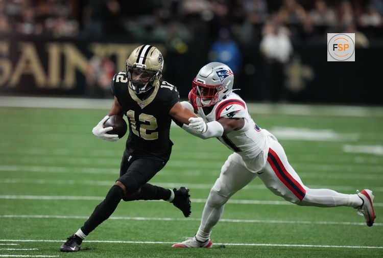 Oct 12, 2025; New Orleans, Louisiana, USA; New Orleans Saints wide receiver Chris Olave (12) runs for a gain past New England Patriots safety Craig Woodson (31) during the second quarter at Caesars Superdome. Credit: Matthew Hinton-Imagn Images
