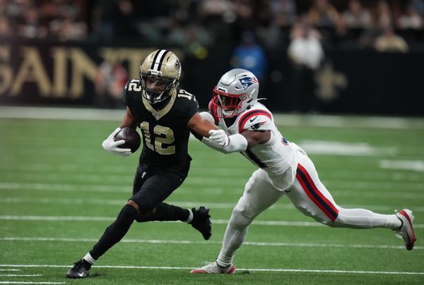 Oct 12, 2025; New Orleans, Louisiana, USA; New Orleans Saints wide receiver Chris Olave (12) runs for a gain past New England Patriots safety Craig Woodson (31) during the second quarter at Caesars Superdome. Mandatory Credit: Matthew Hinton-Imagn Images
