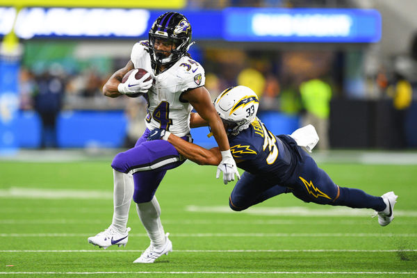 INGLEWOOD, CA - NOVEMBER 26: Los Angeles Chargers defensive back Deane Leonard (33) dives to try and tackle Baltimore Ravens running back Keaton Mitchell (34) during the NFL regular season game between the Baltimore Ravens and the Los Angeles Chargers on November 26, 2023, at SoFi Stadium in Inglewood, CA. (Photo by Brian Rothmuller/Icon Sportswire)