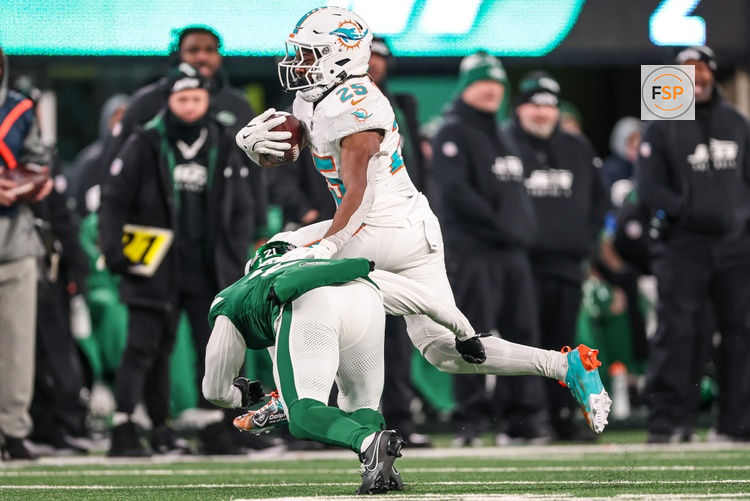 Jan 5, 2025; East Rutherford, New Jersey, USA; Miami Dolphins running back Jaylen Wright (25) fights for yards  as New York Jets safety Ashtyn Davis (21) tackles during the second half at MetLife Stadium. Credit: Vincent Carchietta-Imagn Images