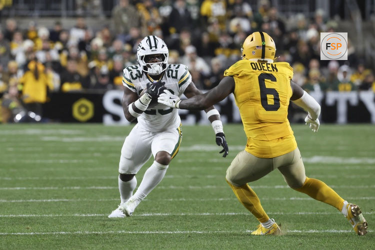 Oct 26, 2025; Pittsburgh, Pennsylvania, USA; Green Bay Packers running back Emanuel Wilson (23) runs the ball against Pittsburgh Steelers linebacker Patrick Queen (6) during the fourth quarter at Acrisure Stadium. Credit: Charles LeClaire-Imagn Images