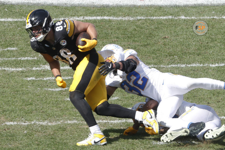 Sep 22, 2024; Pittsburgh, Pennsylvania, USA;  Pittsburgh Steelers tight end Pat Freiermuth (88) runs after a catch as Los Angeles Chargers safety Derwin James Jr. (bottom) and safety Alohi Gilman (32) tackle during the third quarter at Acrisure Stadium. Pittsburgh won 20-10. Credit: Charles LeClaire-Imagn Images