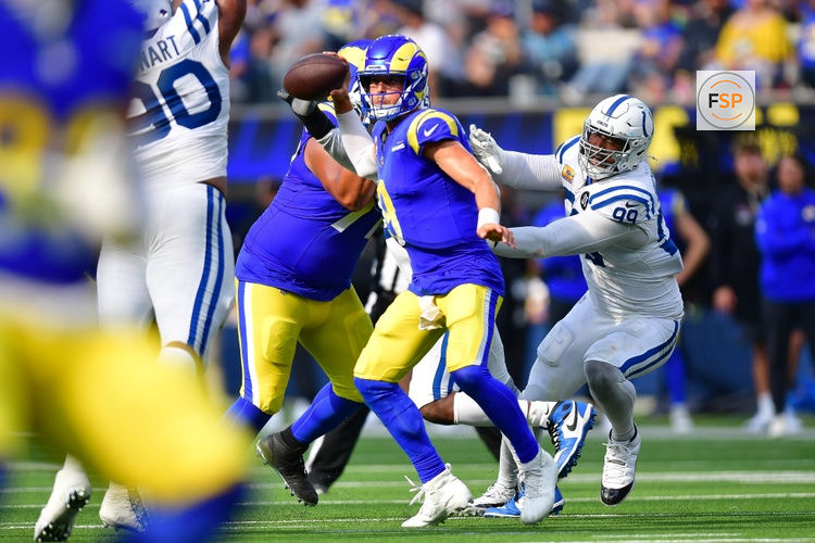 Sep 28, 2025; Inglewood, California, USA; Los Angeles Rams quarterback Matthew Stafford (9) runs out to pass as Indianapolis Colts defensive tackle Deforest Buckner (99) moves in during the second half at SoFi Stadium. Credit: Gary A. Vasquez-Imagn Images