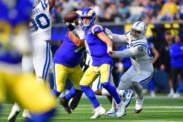 Sep 28, 2025; Inglewood, California, USA; Los Angeles Rams quarterback Matthew Stafford (9) runs out to pass as Indianapolis Colts defensive tackle Deforest Buckner (99) moves in during the second half at SoFi Stadium. Mandatory Credit: Gary A. Vasquez-Imagn Images