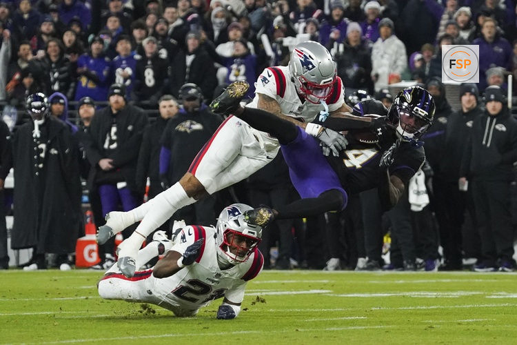 Dec 21, 2025; Baltimore, Maryland, USA;  Baltimore Ravens wide receiver Zay Flowers (4) is hit by New England Patriots cornerback Christian Gonzalez (0) during the first quarter of the game at M&T Bank Stadium. Credit: James Lang-Imagn Images