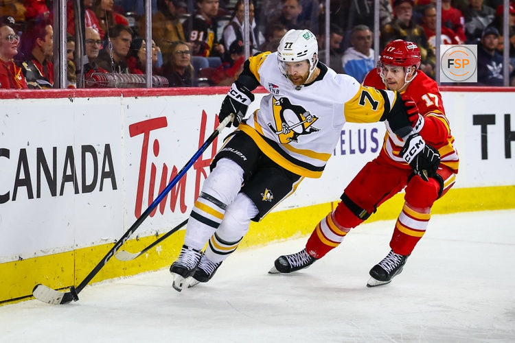 Jan 21, 2026; Calgary, Alberta, CAN; Pittsburgh Penguins defenseman Brett Kulak (77) controls the puck against Calgary Flames center Yegor Sharangovich (17) during the second period at Scotiabank Saddledome. Credit: Sergei Belski-Imagn Images