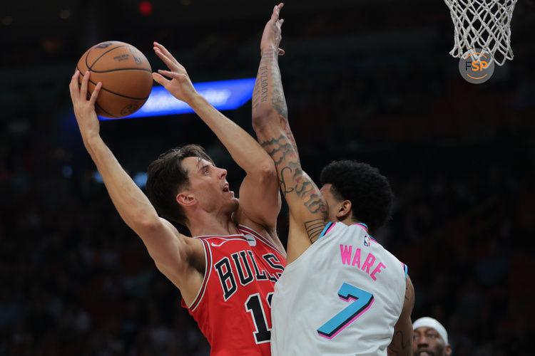 Mar 8, 2025; Miami, Florida, USA; Chicago Bulls forward Zach Collins (12) drives to the basket against Miami Heat center Kel'el Ware (7) during the first quarter at Kaseya Center. Credit: Sam Navarro-Imagn Images