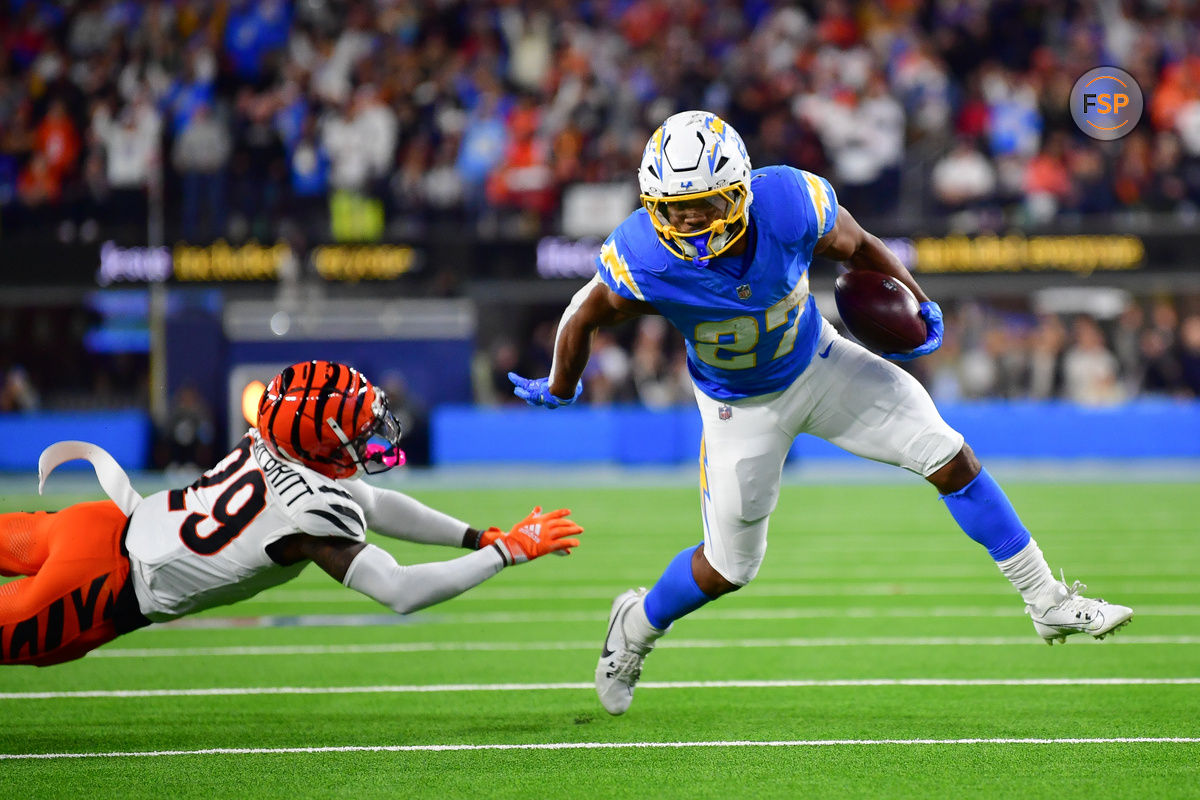 Nov 17, 2024; Inglewood, California, USA; Los Angeles Chargers running back J.K. Dobbins (27) runs the ball ahead of Cincinnati Bengals cornerback Cam Taylor-Britt (29) to score a touchdow during the second half at SoFi Stadium. Credit: Gary A. Vasquez-Imagn Images