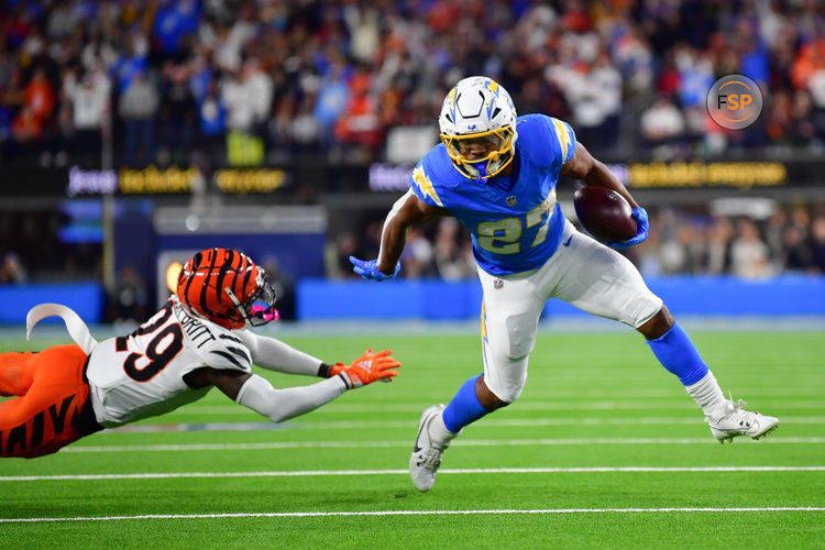 Nov 17, 2024; Inglewood, California, USA; Los Angeles Chargers running back J.K. Dobbins (27) runs the ball ahead of Cincinnati Bengals cornerback Cam Taylor-Britt (29) to score a touchdow during the second half at SoFi Stadium. Credit: Gary A. Vasquez-Imagn Images