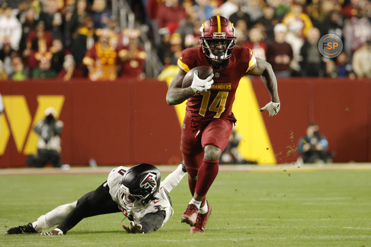 Dec 29, 2024; Landover, Maryland, USA; Washington Commanders wide receiver Olamide Zaccheaus (14) runs with the ball past Atlanta Falcons linebacker Lorenzo Carter (0) during the second half at Northwest Stadium. Credit: Amber Searls-Imagn Images