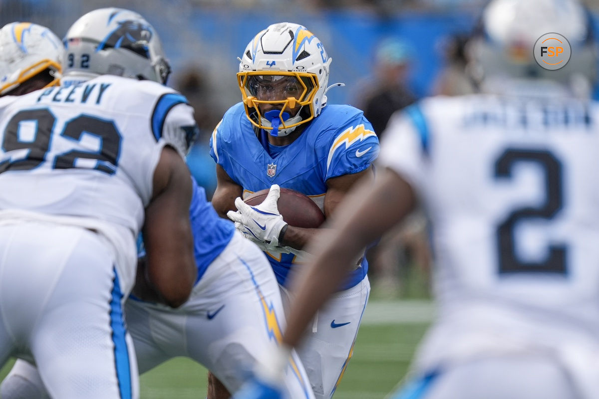 Sep 15, 2024; Charlotte, North Carolina, USA; Los Angeles Chargers running back J.K. Dobbins (27) looks for running room against Carolina Panthers defensive tackle Jayden Perry (92) and cornerback Michael Jackson (2) during the second half at Bank of America Stadium. Credit: Jim Dedmon-Imagn Images