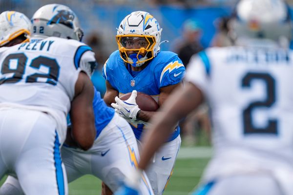 Sep 15, 2024; Charlotte, North Carolina, USA; Los Angeles Chargers running back J.K. Dobbins (27) looks for running room against Carolina Panthers defensive tackle Jayden Perry (92) and cornerback Michael Jackson (2) during the second half at Bank of America Stadium. Mandatory Credit: Jim Dedmon-Imagn Images