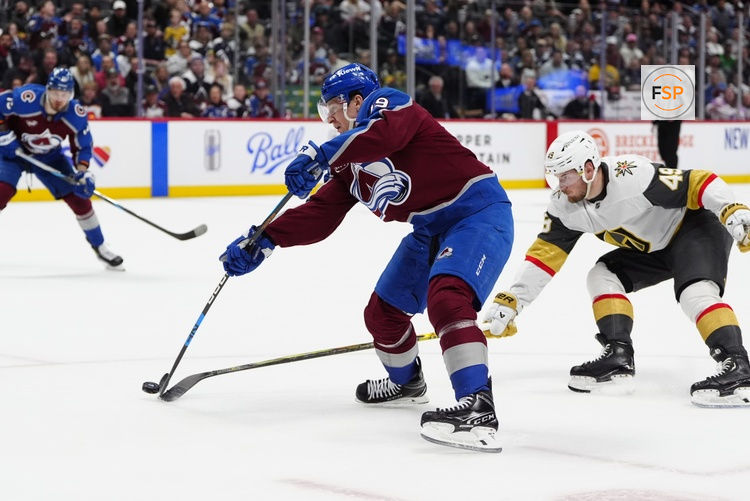 Apr 8, 2025; Denver, Colorado, USA; Colorado Avalanche center Nathan MacKinnon (29) shoots the puck as Vegas Golden Knights center Ivan Barbashev (49) defends in overtime at Ball Arena. Credit: Ron Chenoy-Imagn Images