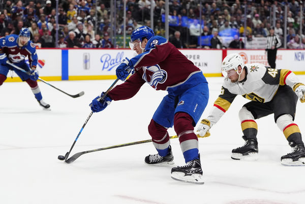 Apr 8, 2025; Denver, Colorado, USA; Colorado Avalanche center Nathan MacKinnon (29) shoots the puck as Vegas Golden Knights center Ivan Barbashev (49) defends in overtime at Ball Arena. Mandatory Credit: Ron Chenoy-Imagn Images
