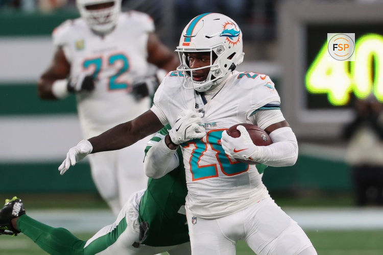 Jan 5, 2025; East Rutherford, New Jersey, USA; Miami Dolphins running back De'Von Achane (28) runs with the ball while New York Jets cornerback D.J. Reed (4) attempts to tackle him during the first quarter at MetLife Stadium. Credit: Ed Mulholland-Imagn Images