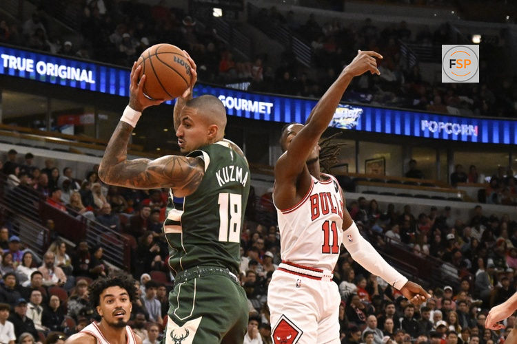 Oct 12, 2025; Chicago, Illinois, USA;  Milwaukee Bucks forward Kyle Kuzma (18) grabs a rebound against Chicago Bulls guard Ayo Dosunmu (11) during the second half at the United Center. Credit: Matt Marton-Imagn Images