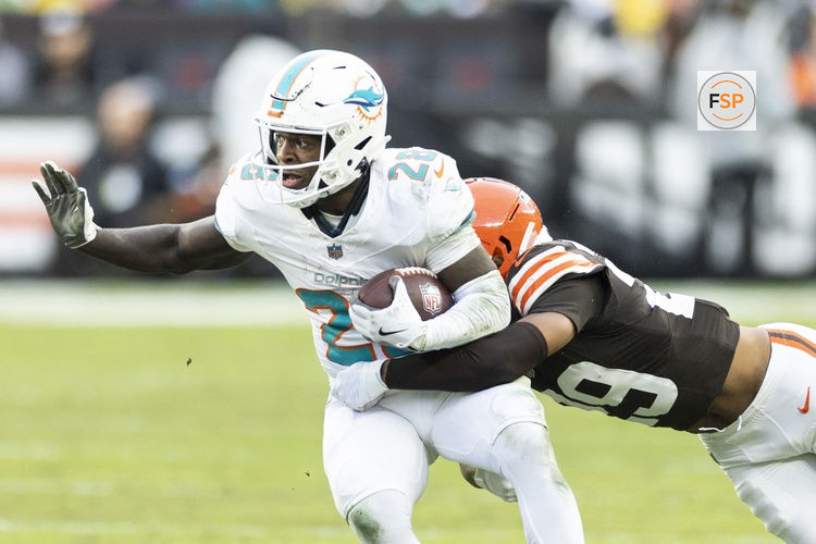 Dec 29, 2024; Cleveland, Ohio, USA; Miami Dolphins running back De'Von Achane (28) runs the ball as Cleveland Browns cornerback Cameron Mitchell (29) tackles him during the first quarter at Huntington Bank Field. Credit: Scott Galvin-Imagn Images