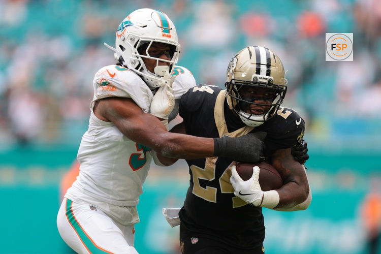 Nov 30, 2025; Miami Gardens, Florida, USA; New Orleans Saints running back Devin Neal (24) carries the ball as Miami Dolphins linebacker K.J. Britt (3) defends during the second half at Hard Rock Stadium. Credit: Sam Navarro-Imagn Images