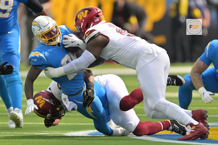 Oct 5, 2025; Inglewood, California, USA; Washington Commanders middle linebacker Bobby Wagner (54) and defensive tackle Jalyn Holmes (96) tackle Los Angeles Chargers running back Hassan Haskins (28) in the first half at SoFi Stadium. Credit: Jayne Kamin-Oncea-Imagn Images