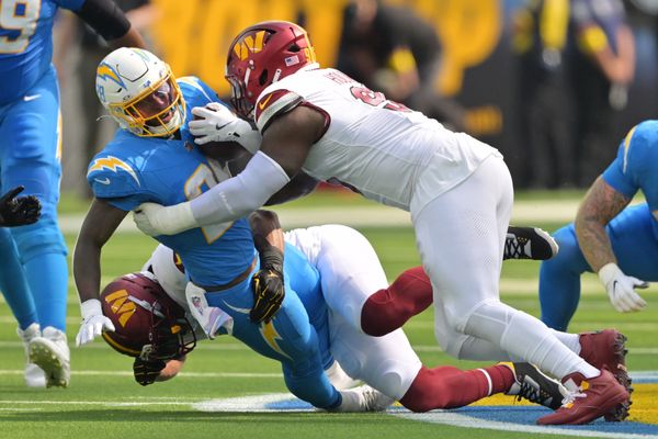 Oct 5, 2025; Inglewood, California, USA; Washington Commanders middle linebacker Bobby Wagner (54) and defensive tackle Jalyn Holmes (96) tackle Los Angeles Chargers running back Hassan Haskins (28) in the first half at SoFi Stadium. Mandatory Credit: Jayne Kamin-Oncea-Imagn Images