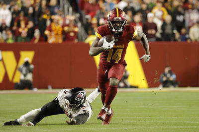 Dec 29, 2024; Landover, Maryland, USA; Washington Commanders wide receiver Olamide Zaccheaus (14) runs with the ball past Atlanta Falcons linebacker Lorenzo Carter (0) during the second half at Northwest Stadium. Mandatory Credit: Amber Searls-Imagn Images