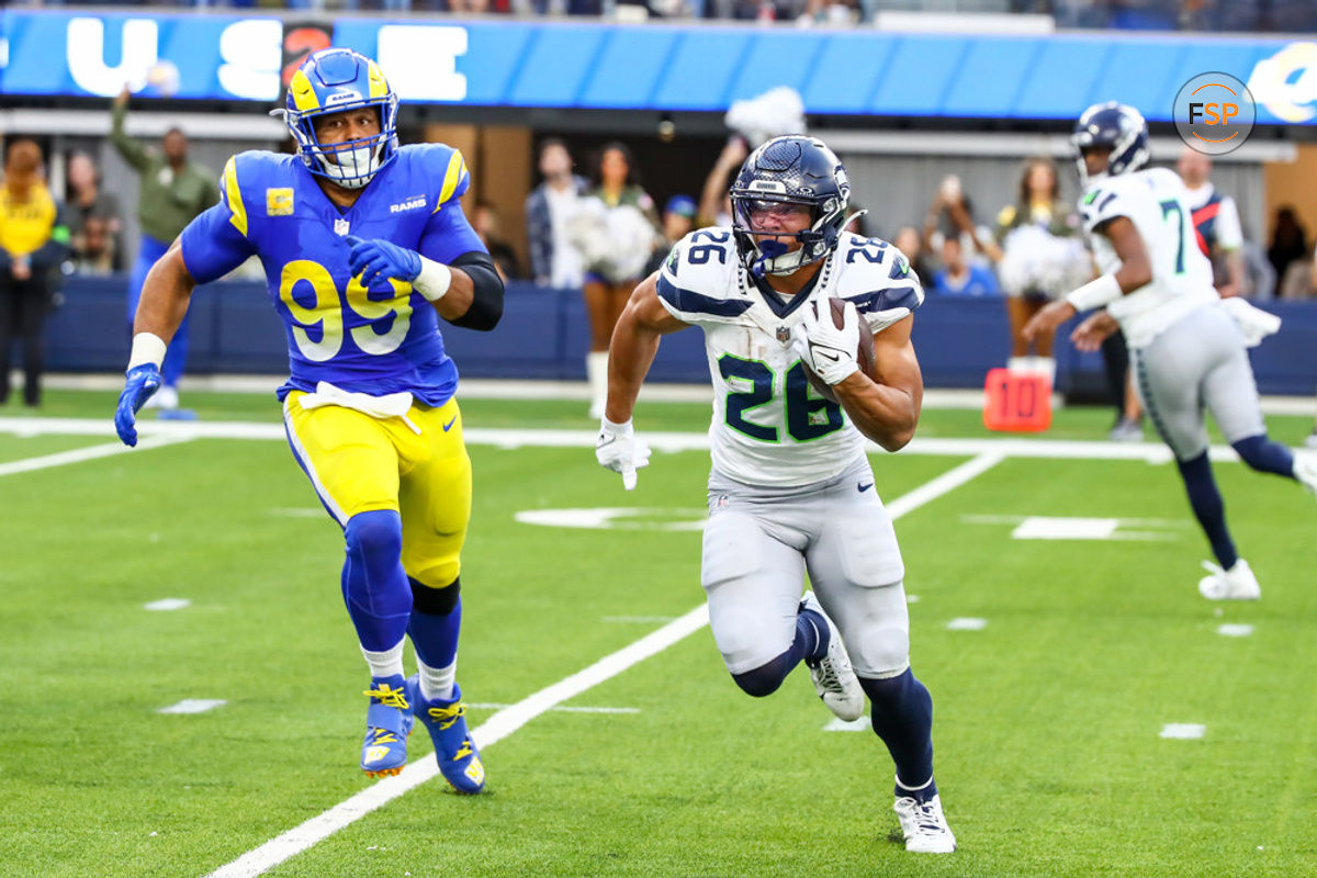 INGLEWOOD, CA - NOVEMBER 19: Seattle Seahawks running back Zach Charbonnet (26) runs away from Los Angeles Rams defensive tackle Aaron Donald (99) during the Seattle Seahawks vs Los Angeles Rams game on November 19, 2023, at SoFi Stadium in Inglewood, CA. (Photo by Jevone Moore/Icon Sportswire)