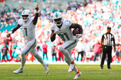 Oct 27, 2024; Miami Gardens, Florida, USA; Miami Dolphins running back Raheem Mostert (31) runs with the football for a touchdown as quarterback Tua Tagovailoa (1) celebrates during the fourth quarter at Hard Rock Stadium. Mandatory Credit: Sam Navarro-Imagn Images