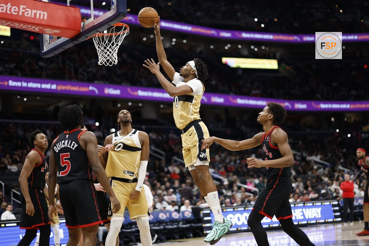 Dec 26, 2025; Washington, District of Columbia, USA; Washington Wizards guard Bilal Coulibaly (0) shoots the ball as Toronto Raptors guard Ochai Agbaji (30) and Raptors guard Immanuel Quickley (5) look on in the second half at Capital One Arena. Credit: Geoff Burke-Imagn Images