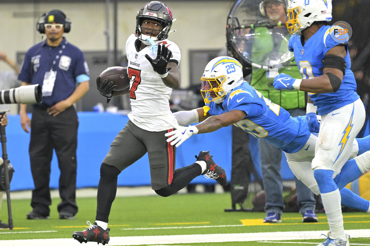 Dec 15, 2024; Inglewood, California, USA; Tampa Bay Buccaneers running back Bucky Irving (7) runs for 54 yards before he is stopped by Los Angeles Chargers cornerback Tarheeb Still (29) and linebacker Daiyan Henley (0) in the second half at SoFi Stadium. Credit: Jayne Kamin-Oncea-Imagn Images