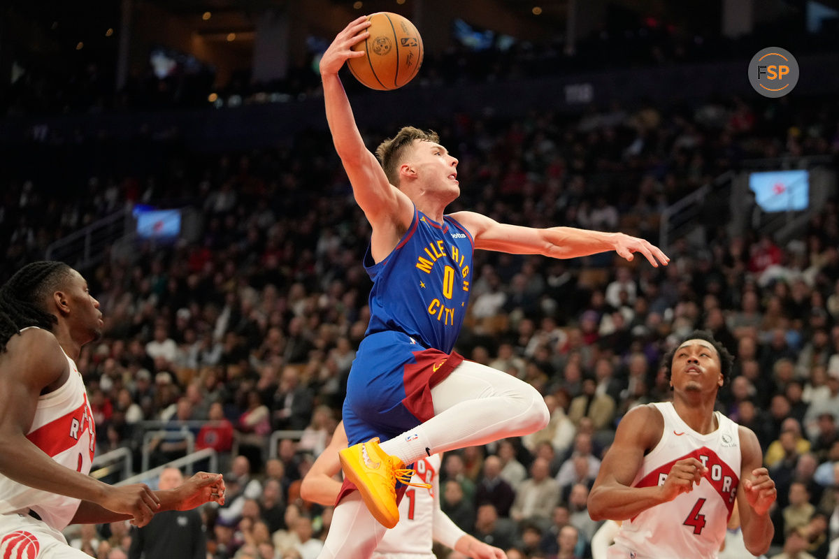 Oct 28, 2024; Toronto, Ontario, CAN; Denver Nuggets guard Christian Braun (0) goes up to dunk the ball as Toronto Raptors forward Scottie Barnes (4) looks on during the first half at Scotiabank Arena. Credit: John E. Sokolowski-Imagn Images