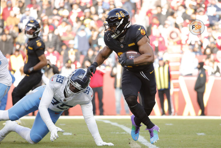 Dec 1, 2024; Landover, Maryland, USA; Washington Commanders running back Jeremy McNichols (26) carries the ball past Tennessee Titans linebacker Ali Gaye (99) during the first half at Northwest Stadium. Credit: Amber Searls-Imagn Images