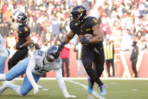 Dec 1, 2024; Landover, Maryland, USA; Washington Commanders running back Jeremy McNichols (26) carries the ball past Tennessee Titans linebacker Ali Gaye (99) during the first half at Northwest Stadium. Mandatory Credit: Amber Searls-Imagn Images