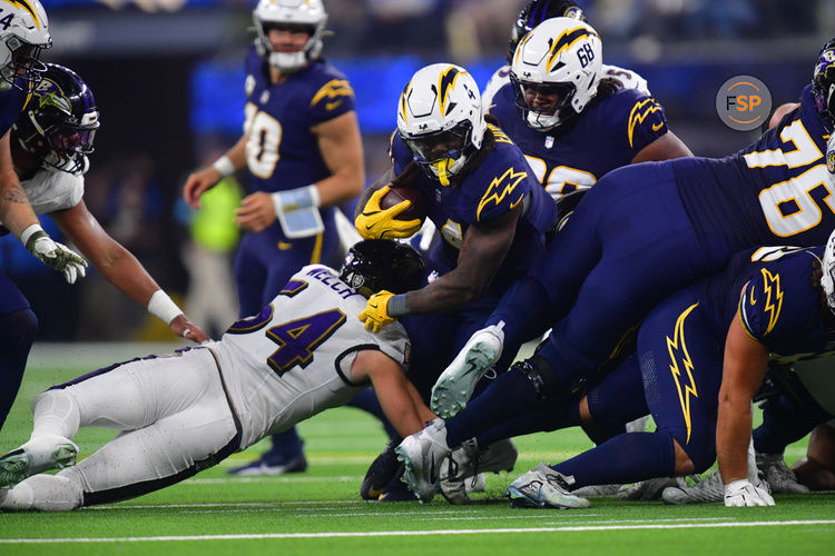 Nov 25, 2024; Inglewood, California, USA; Los Angeles Chargers running back Gus Edwards (4) runs the ball against Baltimore Ravens linebacker Kristian Welch (54) during the first half at SoFi Stadium. Credit: Gary A. Vasquez-Imagn Images