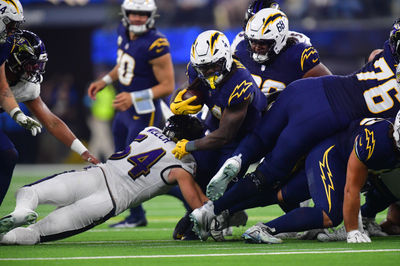 Nov 25, 2024; Inglewood, California, USA; Los Angeles Chargers running back Gus Edwards (4) runs the ball against Baltimore Ravens linebacker Kristian Welch (54) during the first half at SoFi Stadium. Mandatory Credit: Gary A. Vasquez-Imagn Images