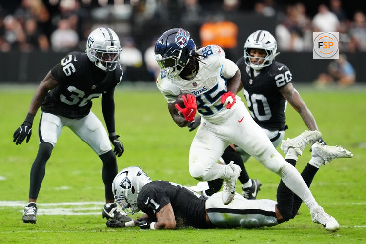 Oct 12, 2025; Paradise, Nevada, USA; Tennessee Titans tight end Chig Okonkwo (85) runs the ball over Las Vegas Raiders wide receiver Tre Tucker (1) during the second half at Allegiant Stadium. Credit: Stephen R. Sylvanie-Imagn Images