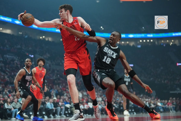 Apr 6, 2025; Portland, Oregon, USA; Portland Trail Blazers center Donovan Clingan (23) handles the ball against San Antonio Spurs center Bismack Biyombo (18) during the first half at Moda Center. Credit: Soobum Im-Imagn Images