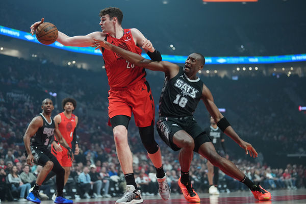 Apr 6, 2025; Portland, Oregon, USA; Portland Trail Blazers center Donovan Clingan (23) handles the ball against San Antonio Spurs center Bismack Biyombo (18) during the first half at Moda Center. Mandatory Credit: Soobum Im-Imagn Images