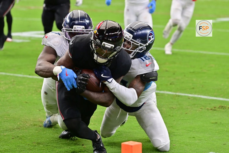 Oct 5, 2025; Glendale, Arizona, USA; Arizona Cardinals running back Bam Knight (20) it tackled short of the goal line by Tennessee Titans linebacker Oluwafemi Oladejo (7) and cornerback Jalyn Armour-Davis (18) during the second quarter at State Farm Stadium. Credit: Matt Kartozian-Imagn Images