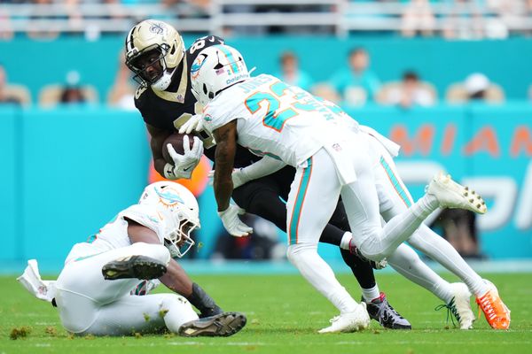 Nov 30, 2025; Miami Gardens, Florida, USA; New Orleans Saints tight end Juwan Johnson (83) is tackled by Miami Dolphins cornerback Jack Jones (23) during the first half at Hard Rock Stadium. Mandatory Credit: Rich Storry-Imagn Images