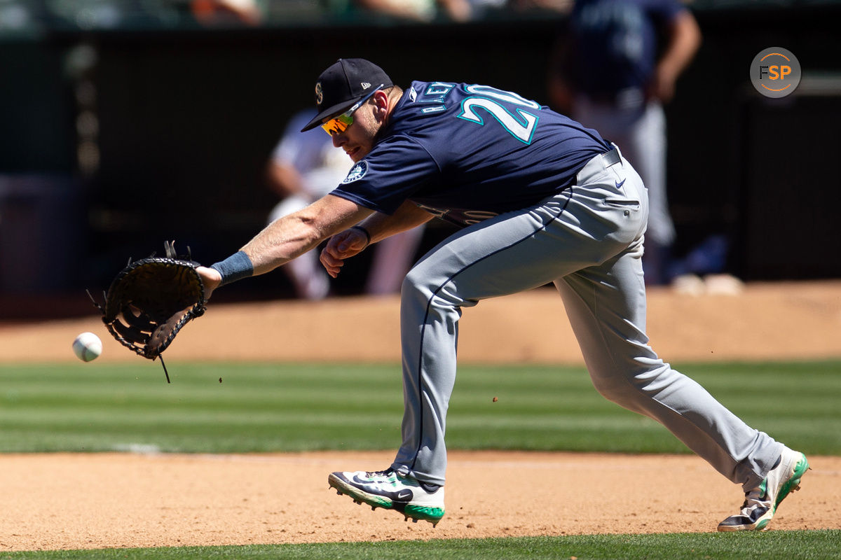 Sep 5, 2024; Oakland, California, USA; Seattle Mariners first baseman Luke Raley (20) attempts to field a ball hit by Oakland Athletics right fielder Lawrence Butler (not pictured) during the seventh inning at Oakland-Alameda County Coliseum. Credit: D. Ross Cameron-Imagn Images