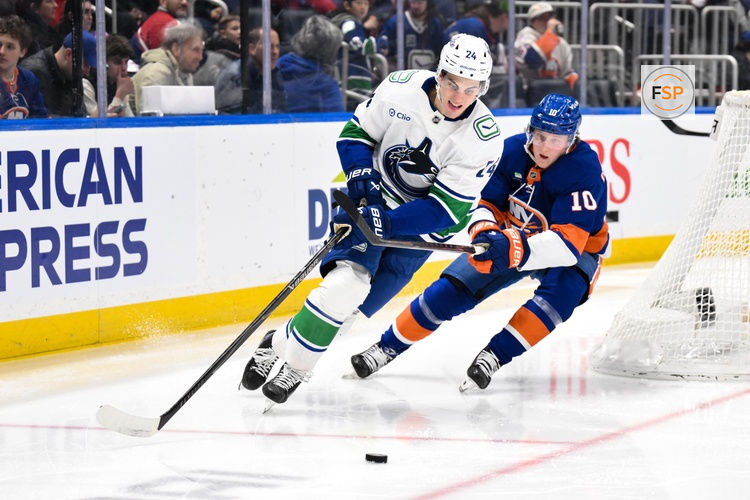 Dec 19, 2025; Elmont, New York, USA; Vancouver Canucks defenseman Zeev Buium (24) skates with the puck while defended by New York Islanders right wing Simon Holmstrom (10) during the second period at UBS Arena. Credit: John Jones-Imagn Images