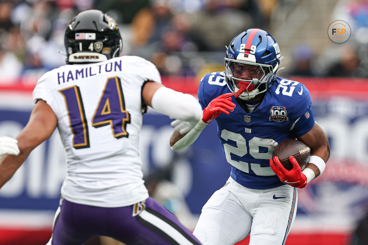 Dec 15, 2024; East Rutherford, New Jersey, USA; New York Giants running back Tyrone Tracy Jr. (29) carries the ball asBaltimore Ravens safety Kyle Hamilton (14) pursues during the first half at MetLife Stadium. Credit: Vincent Carchietta-Imagn Images