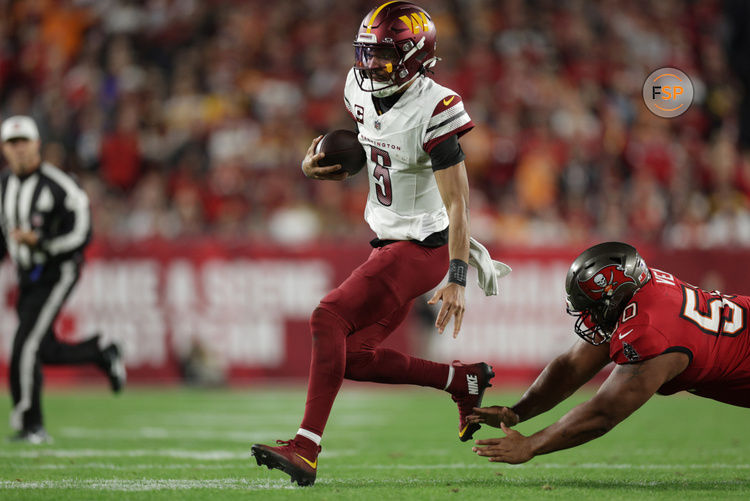 Jan 12, 2025; Tampa, Florida, USA; Washington Commanders quarterback Jayden Daniels (5) scrambles against Tampa Bay Buccaneers defensive tackle Vita Vea (50) during the second quarter of a NFC wild card playoff at Raymond James Stadium. Credit: Nathan Ray Seebeck-Imagn Images