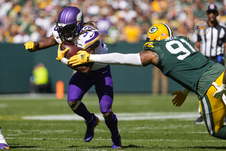 Sep 29, 2024; Green Bay, Wisconsin, USA;  Minnesota Vikings running back Aaron Jones (33) rushes with the football as Green Bay Packers defensive lineman Preston Smith (91) defends during the second quarter at Lambeau Field. Credit: Jeff Hanisch-Imagn Images