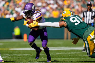 Sep 29, 2024; Green Bay, Wisconsin, USA;  Minnesota Vikings running back Aaron Jones (33) rushes with the football as Green Bay Packers defensive lineman Preston Smith (91) defends during the second quarter at Lambeau Field. Mandatory Credit: Jeff Hanisch-Imagn Images