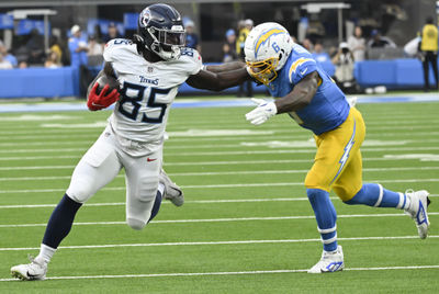 Nov 10, 2024; Inglewood, California, USA; Tennessee Titans tight end Chig Okonkwo (85) stiff arms Los Angeles Chargers linebacker Denzel Perryman (6) during the third quarter at SoFi Stadium. Mandatory Credit: Robert Hanashiro-Imagn Images